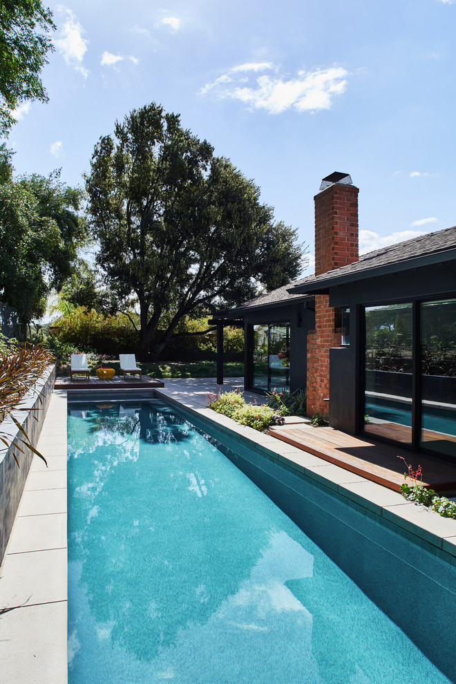 Imagen de piscina alargada vintage de tamaño medio rectangular en patio trasero con losas de hormigón