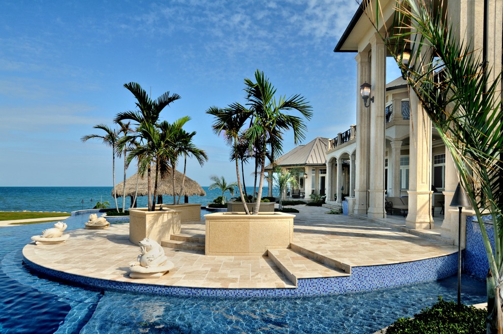 Идея дизайна: огромный бассейн-инфинити произвольной формы на заднем дворе в средиземноморском стиле с фонтаном и покрытием из плитки