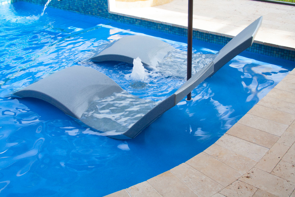 Großer Moderner Pool hinter dem Haus in individueller Form mit Wasserspiel und Natursteinplatten in Miami