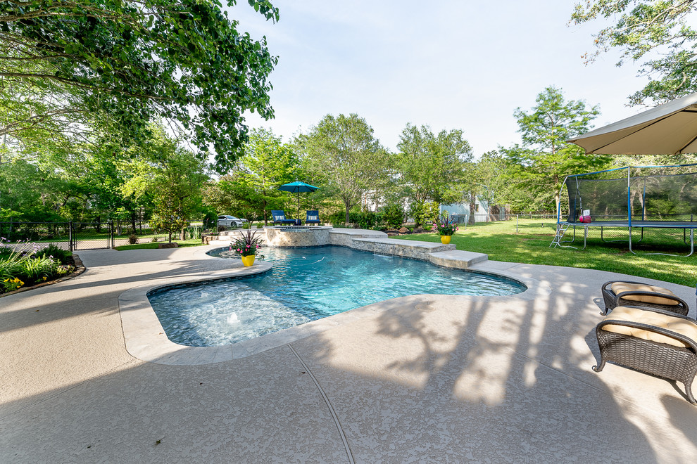 Cette photo montre une piscine naturelle et arrière exotique de taille moyenne et sur mesure avec un bain bouillonnant et une terrasse en bois.