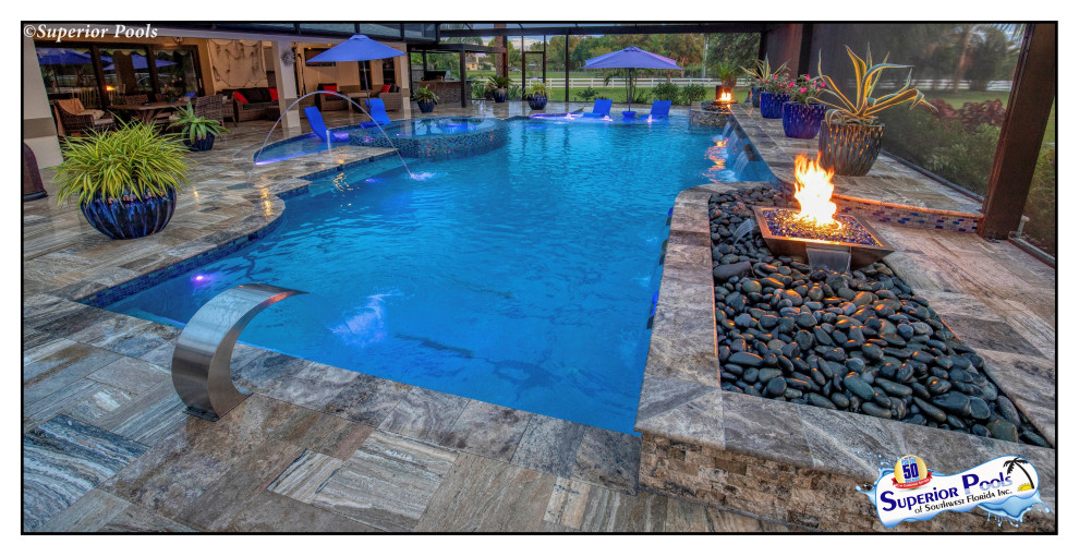 Huge island style backyard custom-shaped pool photo in Tampa with decking