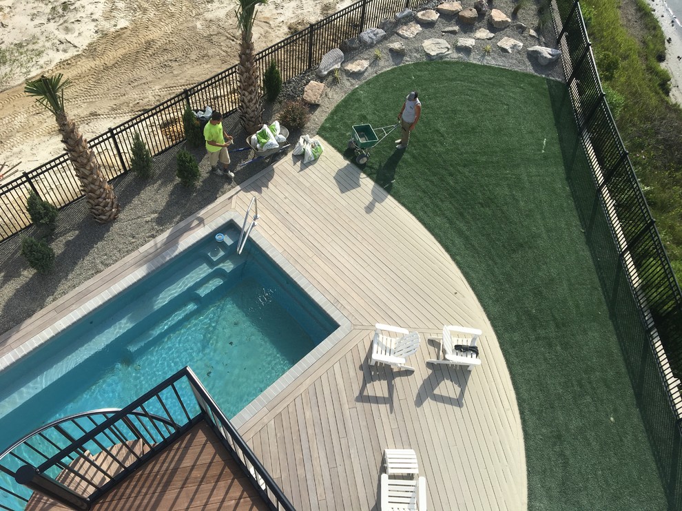 Modelo de piscina natural marinera pequeña rectangular en patio lateral con entablado
