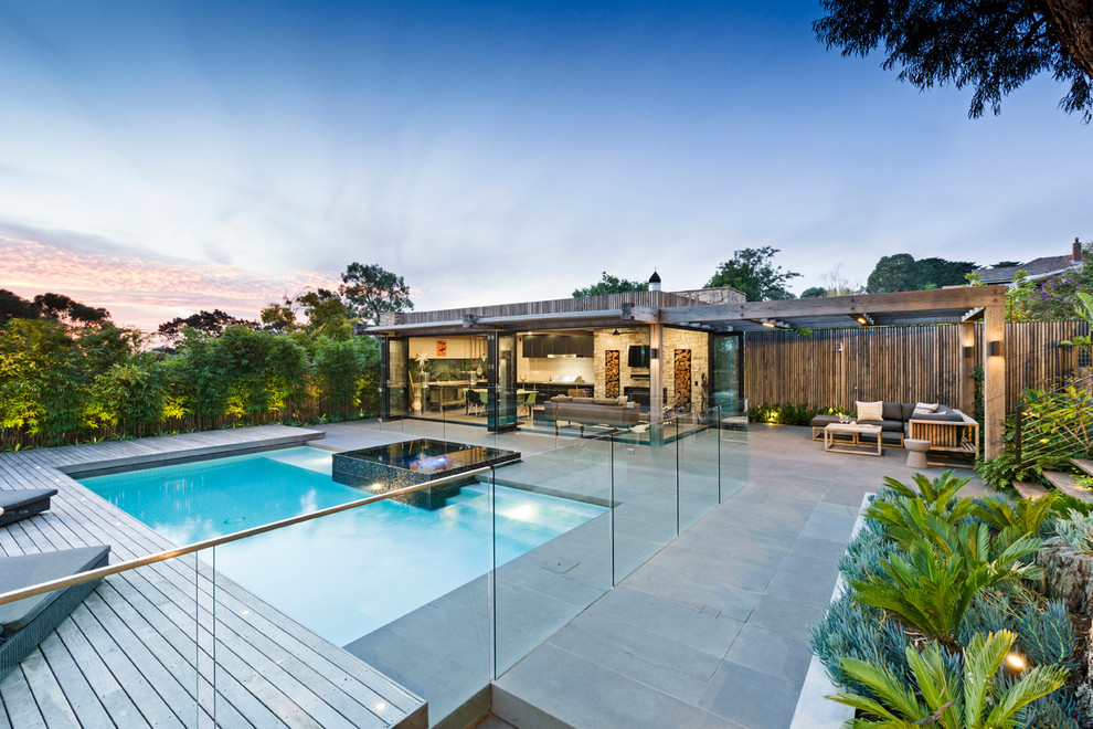 Immagine di una piscina monocorsia contemporanea rettangolare dietro casa con una dépendance a bordo piscina e pavimentazioni in cemento