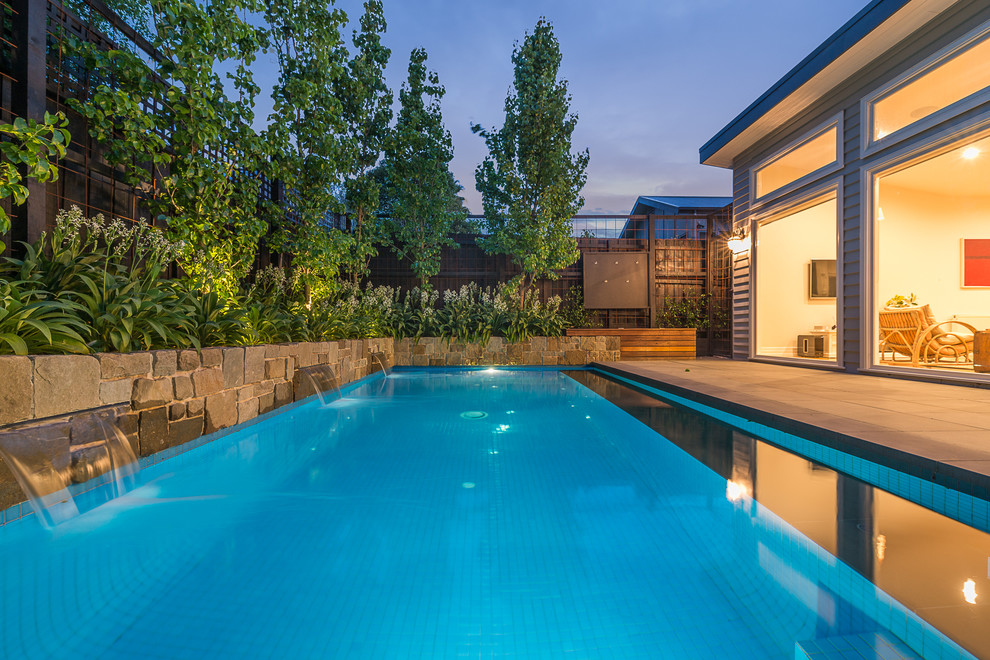 Esempio di una piccola piscina monocorsia minimal rettangolare dietro casa con pavimentazioni in pietra naturale e fontane