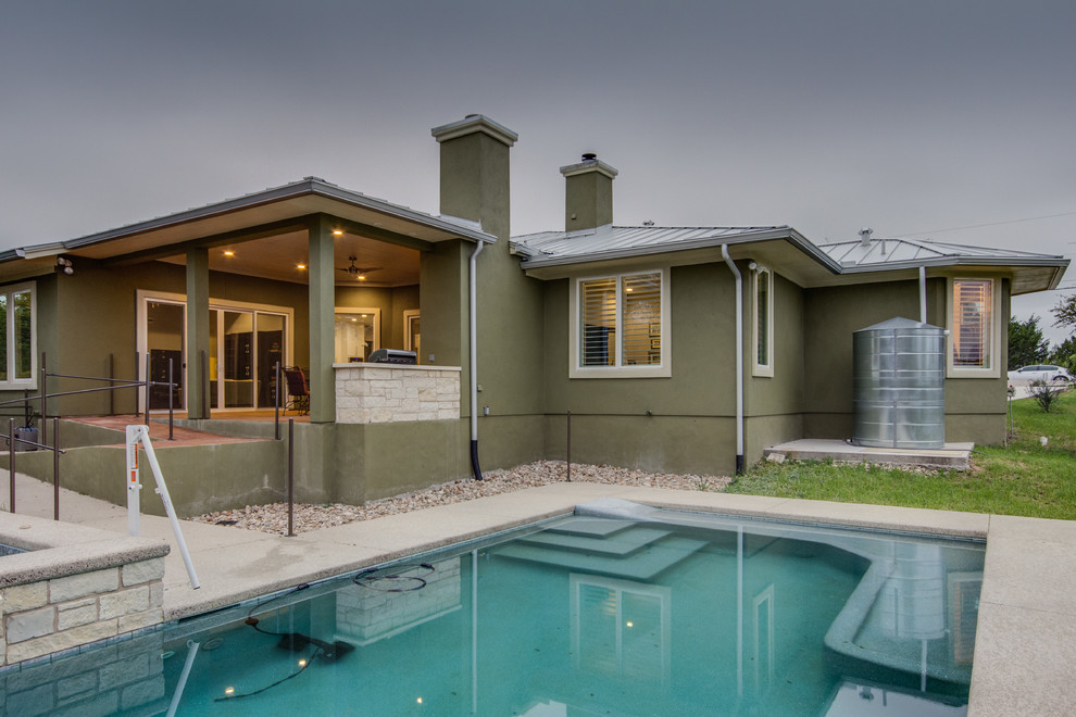 Immagine di una piscina monocorsia chic rettangolare di medie dimensioni e dietro casa con una vasca idromassaggio e lastre di cemento