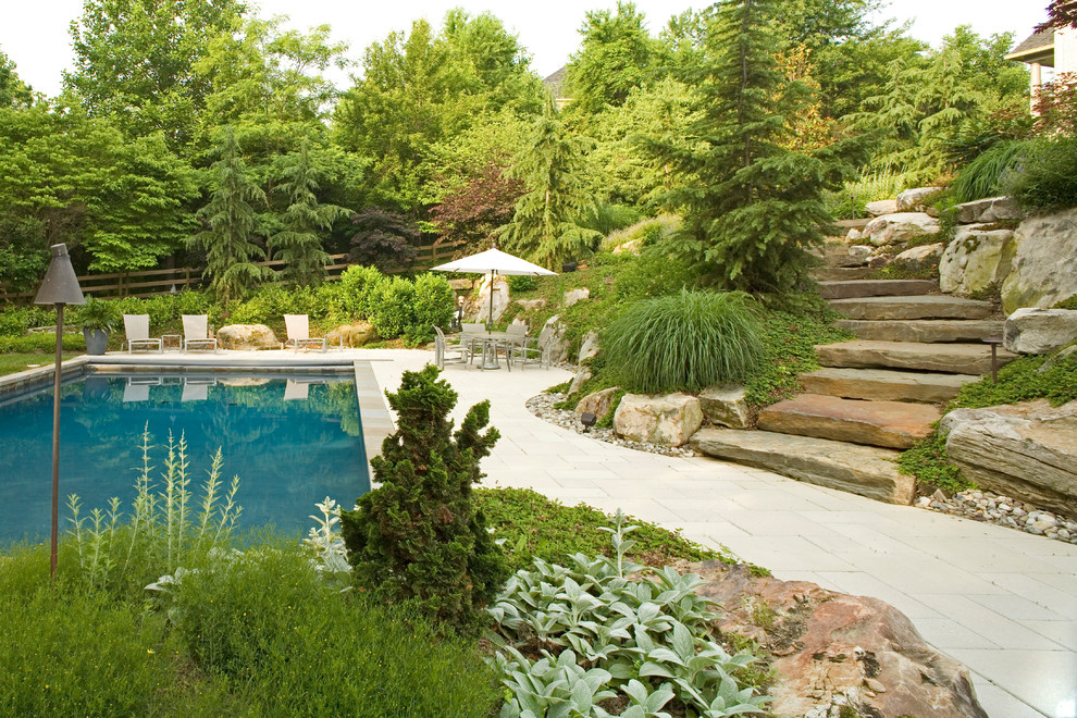 Foto de piscina alargada rústica de tamaño medio rectangular en patio trasero con adoquines de hormigón