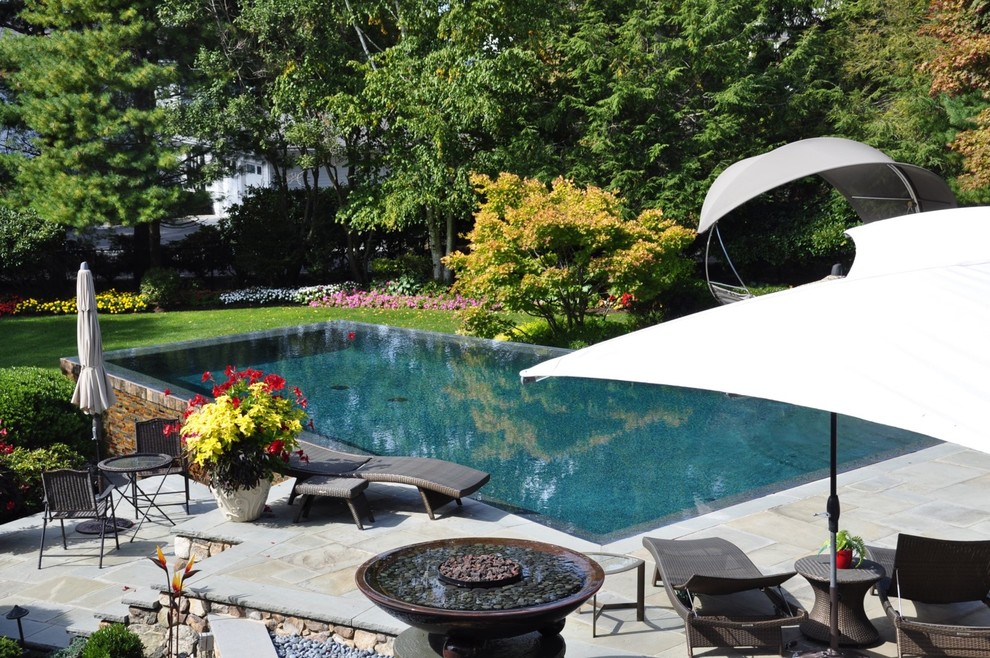 Großer Skandinavischer Infinity-Pool hinter dem Haus in rechteckiger Form mit Natursteinplatten in Boston