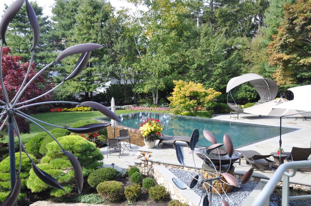 Großer Skandinavischer Infinity-Pool hinter dem Haus in rechteckiger Form mit Natursteinplatten in Boston