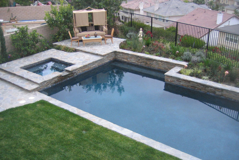 Foto de piscinas y jacuzzis alargados tradicionales de tamaño medio en forma de L en patio trasero con adoquines de piedra natural