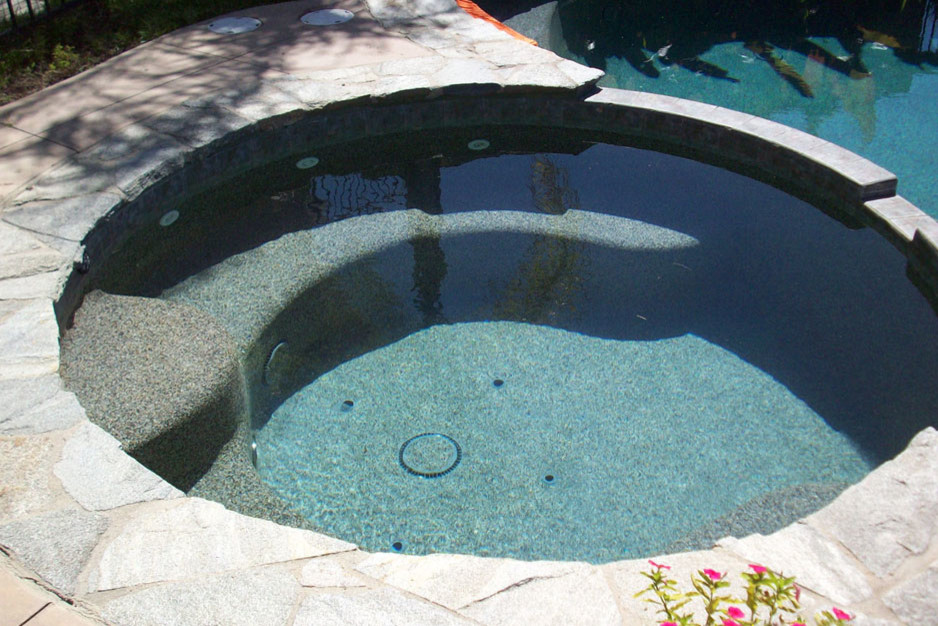 Diseño de piscinas y jacuzzis alargados tradicionales pequeños redondeados en patio trasero con losas de hormigón