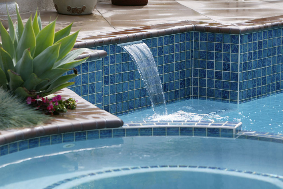 Immagine di una piscina monocorsia classica di medie dimensioni e dietro casa con fontane e lastre di cemento