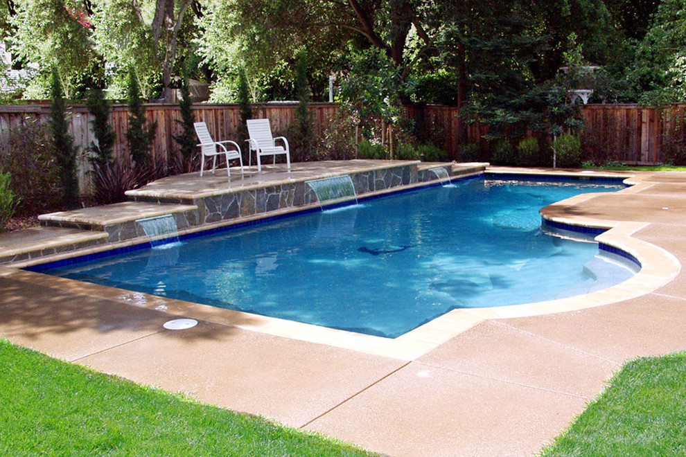 Modelo de piscina con fuente alargada tradicional de tamaño medio a medida en patio trasero con adoquines de hormigón