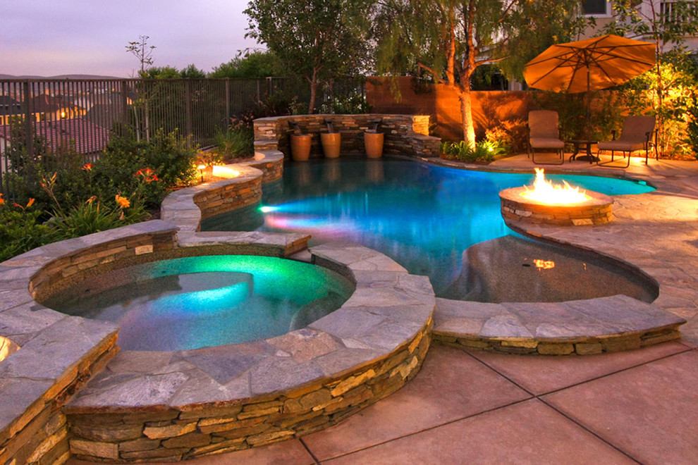Esempio di una grande piscina classica personalizzata dietro casa con una vasca idromassaggio e pavimentazioni in pietra naturale