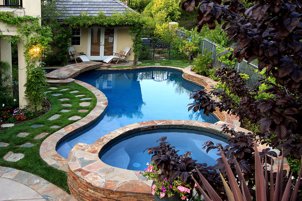 Exemple d'une piscine naturelle et arrière chic en forme de haricot de taille moyenne avec un bain bouillonnant et des pavés en pierre naturelle.