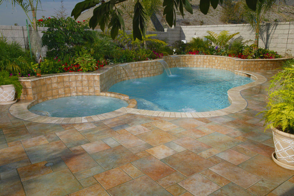 Idee per una piscina naturale classica a "C" di medie dimensioni e dietro casa con una vasca idromassaggio e pavimentazioni in pietra naturale