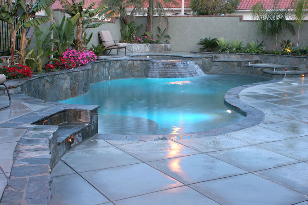 Exemple d'une piscine naturelle et arrière tendance en forme de haricot de taille moyenne avec un bain bouillonnant et des pavés en béton.