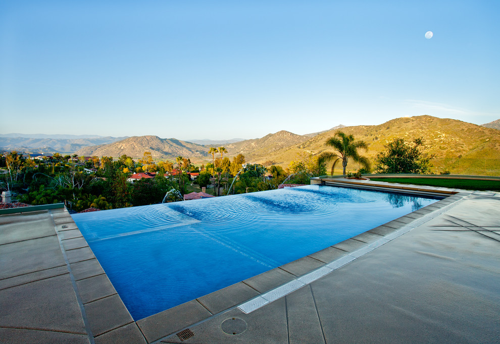Imagen de piscinas y jacuzzis infinitos actuales de tamaño medio rectangulares en patio trasero con losas de hormigón