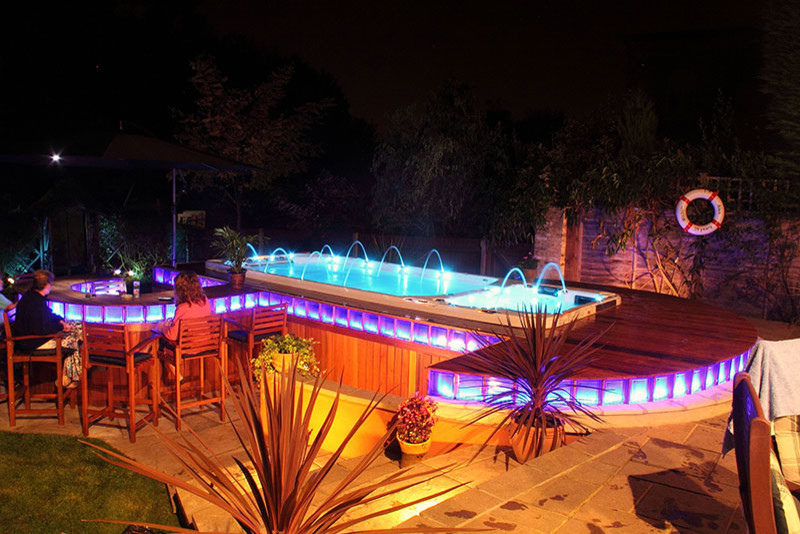 Exemple d'une piscine arrière moderne de taille moyenne et rectangle avec un bain bouillonnant et une terrasse en bois.