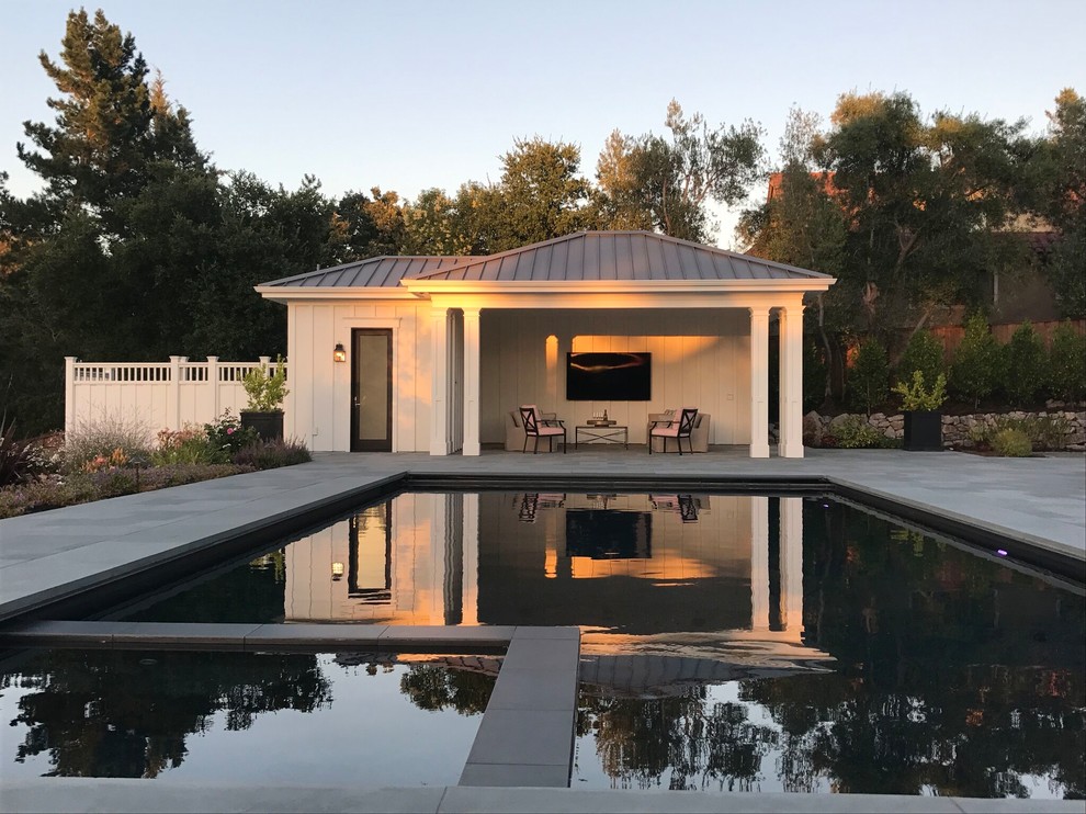 Foto di una grande piscina monocorsia moderna rettangolare dietro casa con una dépendance a bordo piscina e lastre di cemento