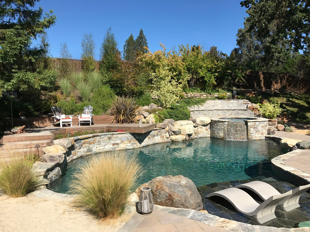 Modelo de piscinas y jacuzzis naturales minimalistas grandes a medida en patio trasero con adoquines de piedra natural