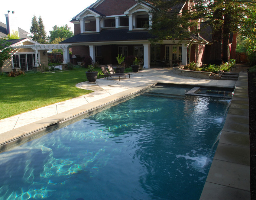 Foto di una grande piscina monocorsia minimalista rettangolare dietro casa con fontane e cemento stampato