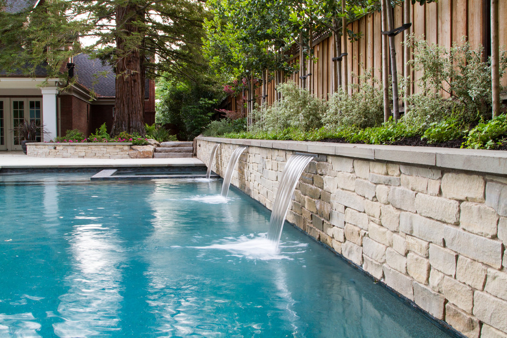 Ejemplo de piscina con fuente alargada moderna grande rectangular en patio trasero con suelo de hormigón estampado