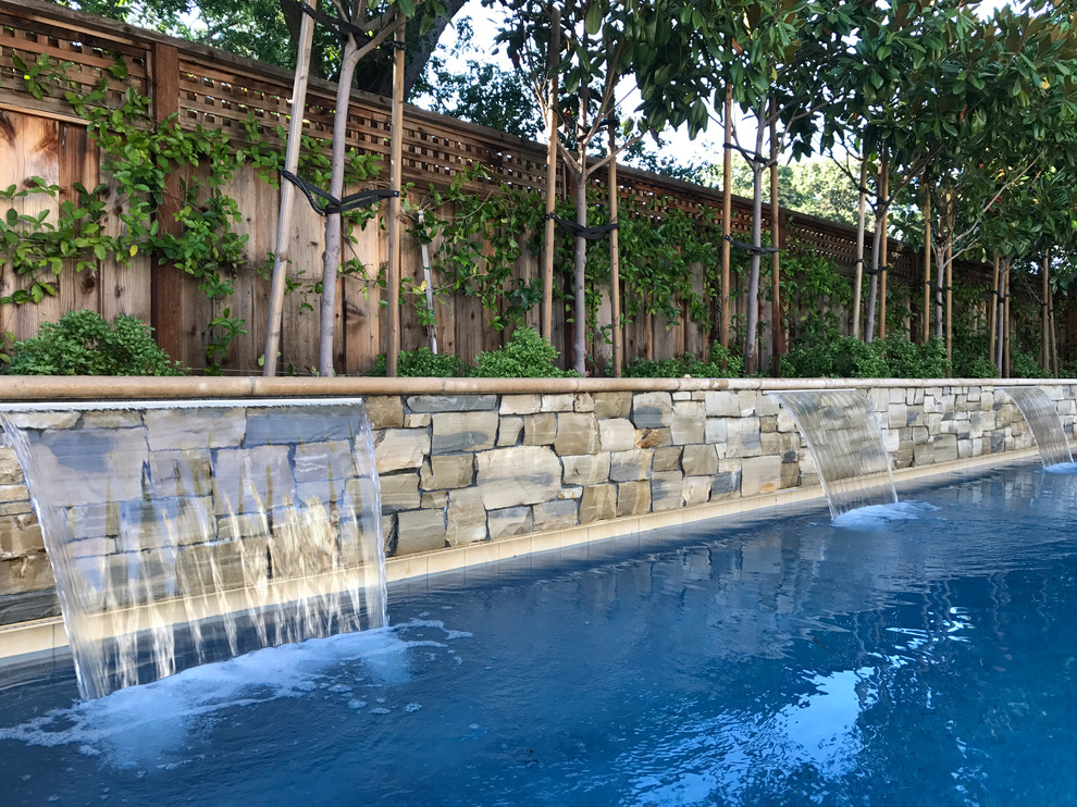Immagine di una grande piscina monocorsia minimalista rettangolare dietro casa con fontane e pavimentazioni in pietra naturale