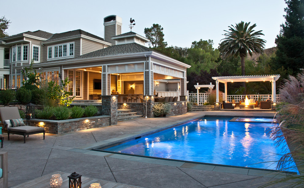 Immagine di una grande piscina monocorsia moderna rettangolare dietro casa con una vasca idromassaggio e cemento stampato