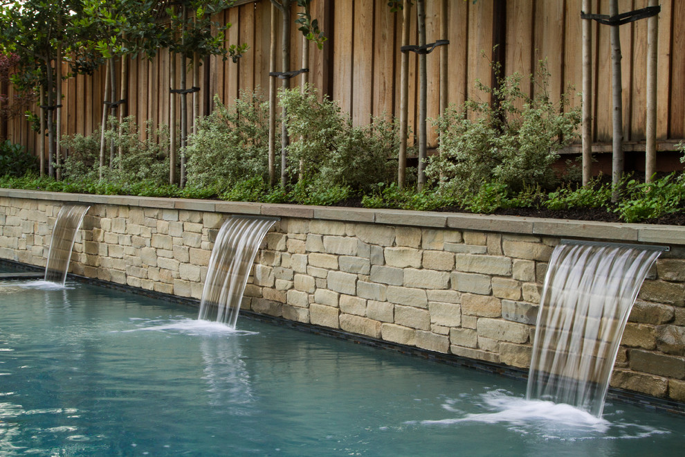 Esempio di una grande piscina monocorsia moderna rettangolare dietro casa con fontane e cemento stampato