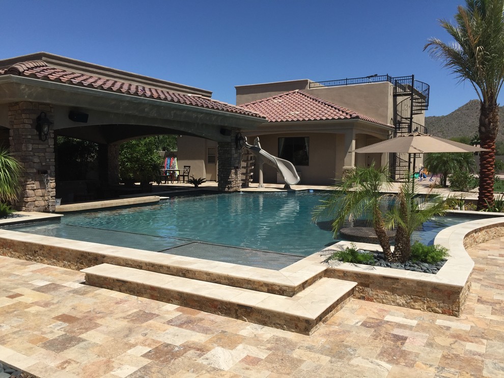 Foto de piscina con tobogán alargada clásica renovada grande rectangular en patio trasero con adoquines de piedra natural