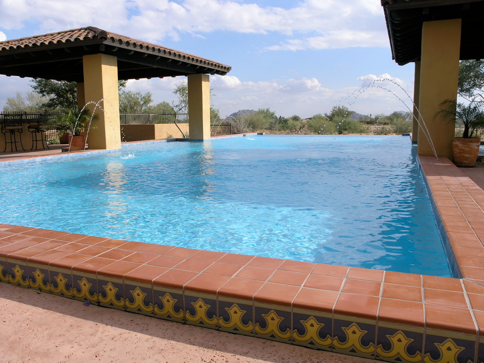 Aménagement d'une grande piscine à débordement et arrière sud-ouest américain rectangle avec un point d'eau et des pavés en béton.