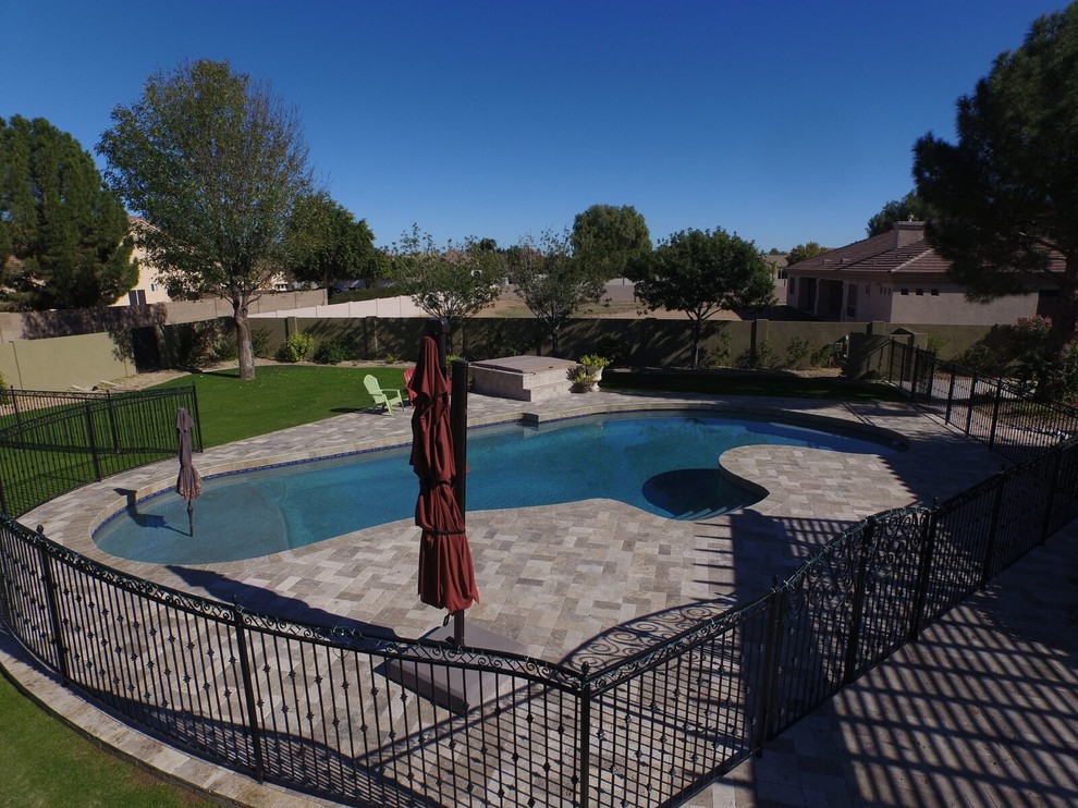 Foto de piscina clásica grande a medida en patio trasero con adoquines de piedra natural