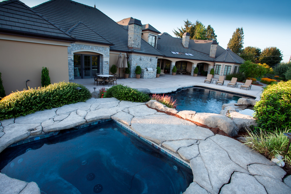 Modelo de piscinas y jacuzzis de estilo de casa de campo grandes a medida en patio trasero con suelo de hormigón estampado