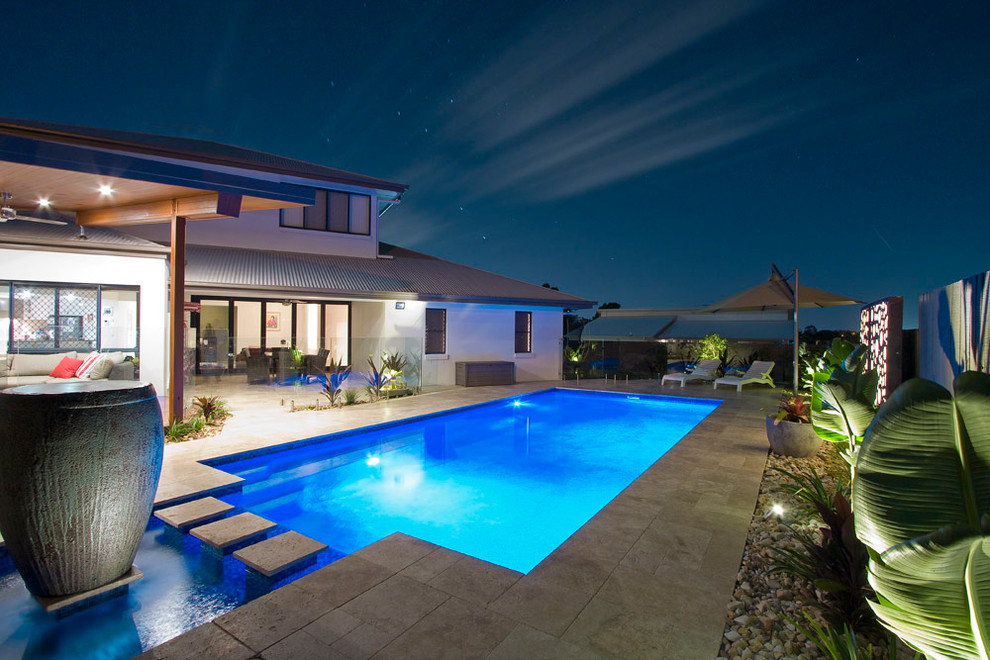 This is an example of a large modern back rectangular swimming pool in Brisbane with a water feature and tiled flooring.