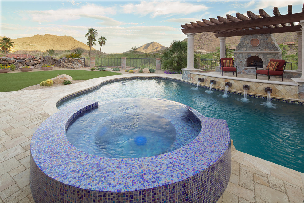 This is an example of a large mediterranean back custom shaped natural swimming pool in Phoenix with a pool house and natural stone paving.
