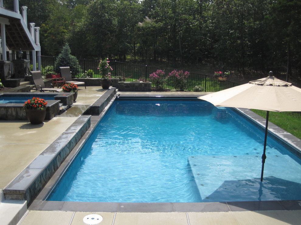 Ejemplo de piscinas y jacuzzis naturales clásicos de tamaño medio rectangulares en patio trasero con losas de hormigón