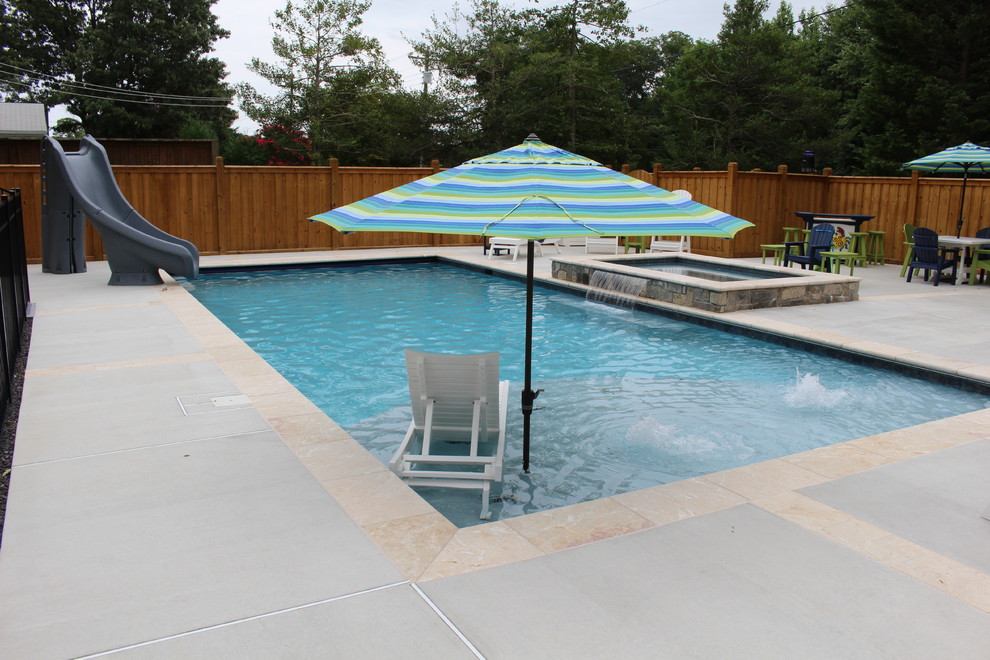 Cette photo montre une piscine naturelle et avant chic de taille moyenne et rectangle avec un toboggan et une terrasse en bois.