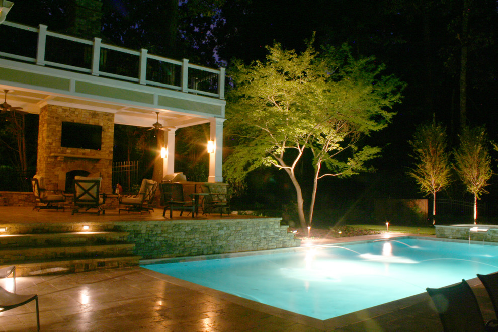 Idée de décoration pour une grande piscine arrière tradition rectangle avec un bain bouillonnant et des pavés en pierre naturelle.