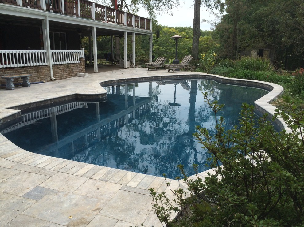 Foto de piscina alargada clásica grande a medida en patio trasero con adoquines de hormigón