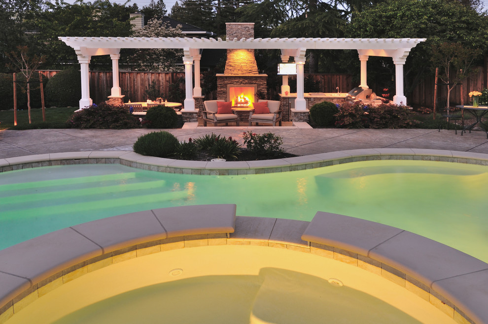 Ejemplo de piscina con fuente natural clásica extra grande a medida en patio trasero con suelo de hormigón estampado