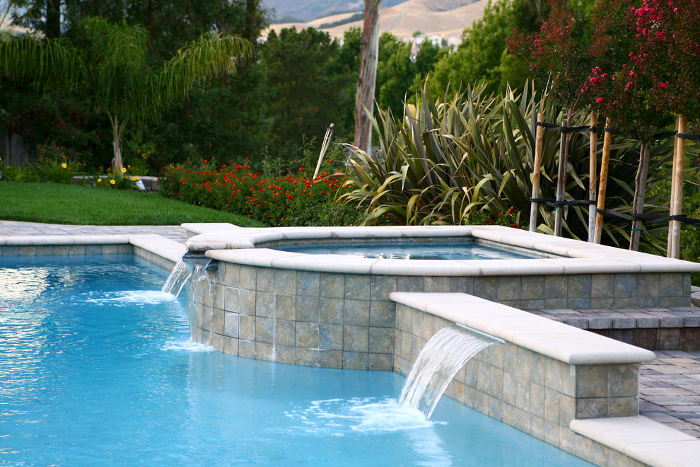 Imagen de piscina con fuente clásica de tamaño medio rectangular en patio trasero con adoquines de hormigón