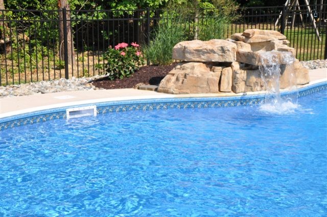 На фото: бассейн среднего размера, произвольной формы на заднем дворе в морском стиле с фонтаном и покрытием из бетонных плит