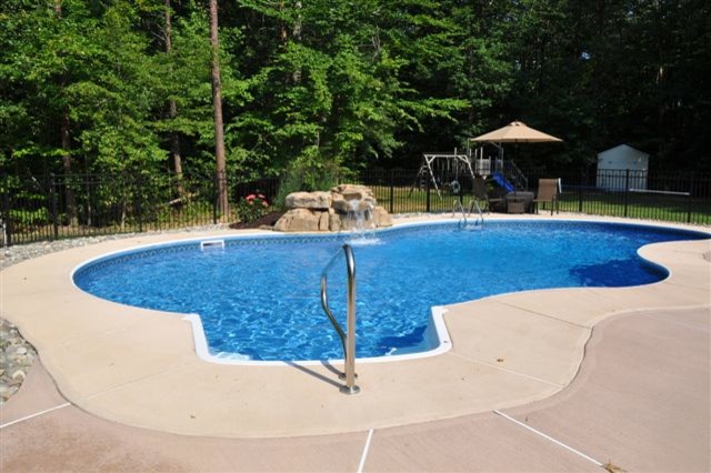 Esempio di una piscina tropicale personalizzata di medie dimensioni e dietro casa con fontane e lastre di cemento