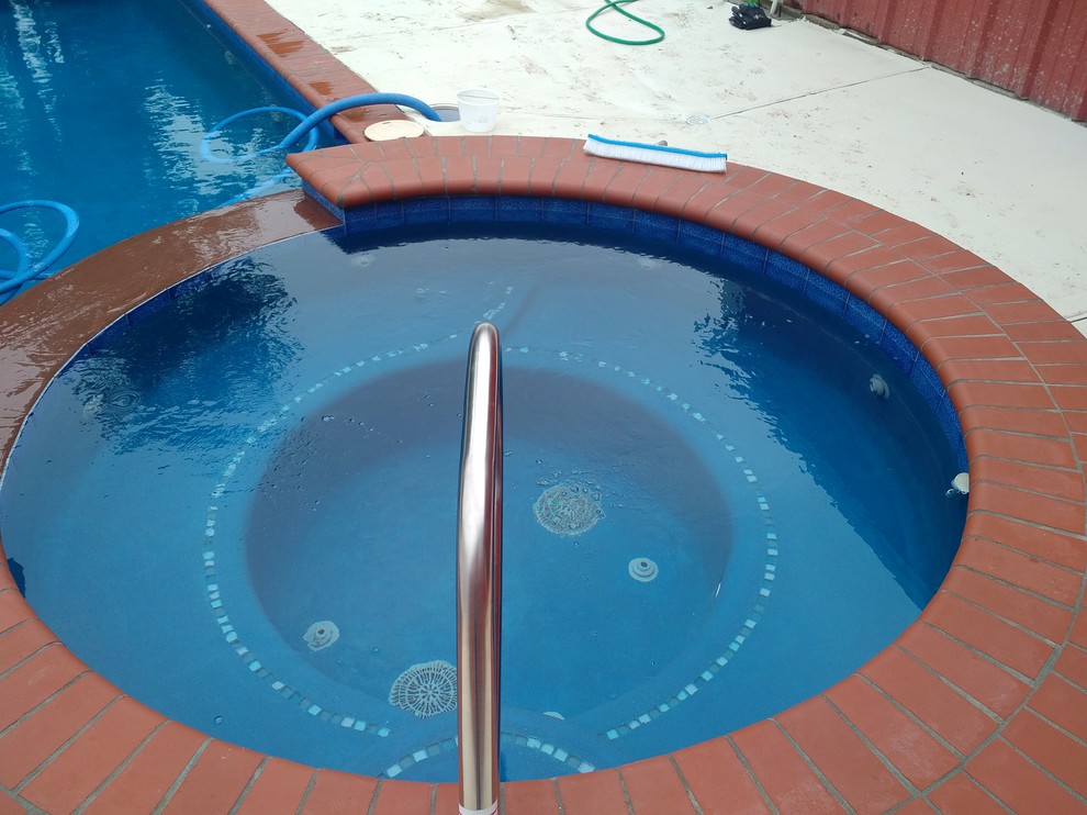 Immagine di una piscina monocorsia country rettangolare di medie dimensioni e dietro casa con una vasca idromassaggio e lastre di cemento
