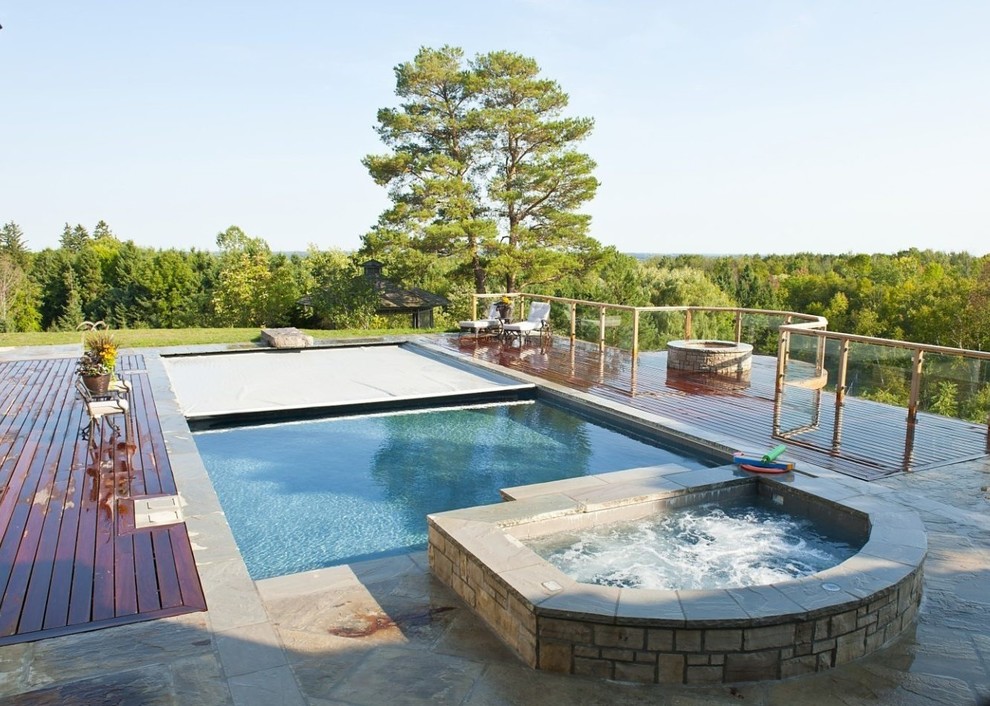 Ejemplo de piscina de estilo americano grande rectangular en patio trasero con entablado