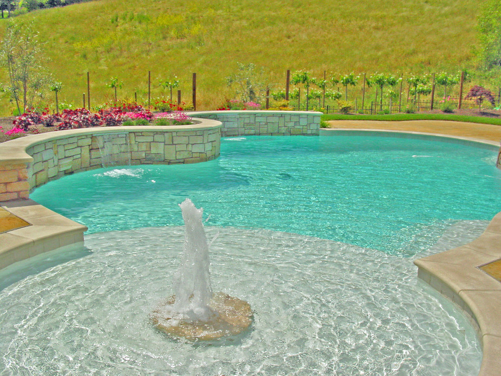 Ispirazione per una grande piscina monocorsia mediterranea personalizzata dietro casa con fontane e cemento stampato