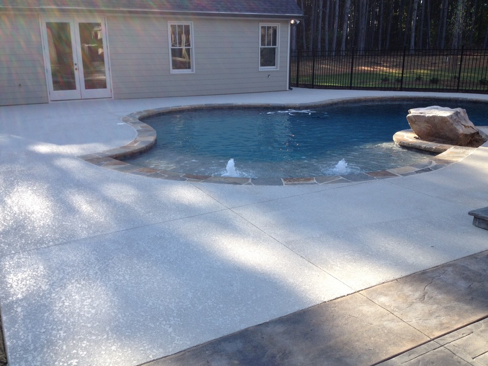 Esempio di una grande piscina naturale stile americano personalizzata dietro casa con pedane