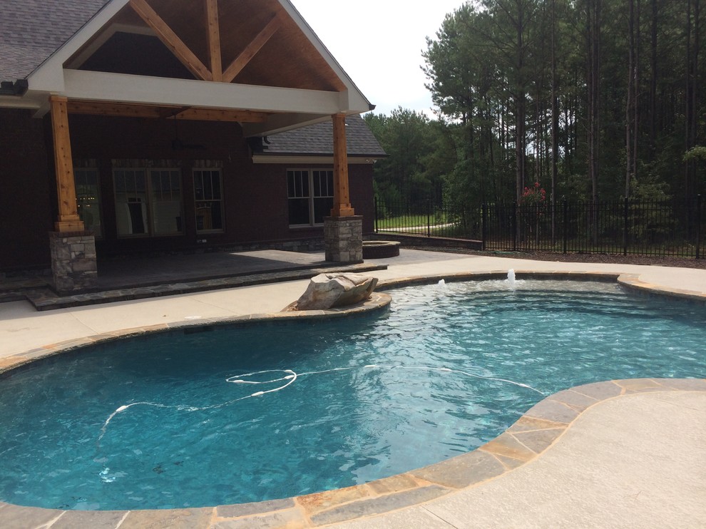 Diseño de piscina natural de estilo americano grande a medida en patio trasero con entablado