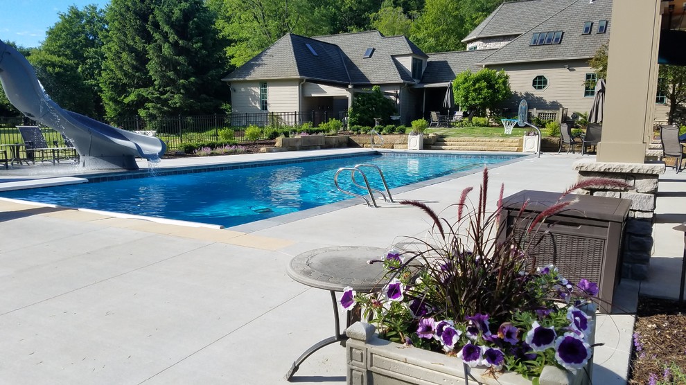 Idee per una grande piscina monocorsia classica rettangolare dietro casa con un acquascivolo e lastre di cemento