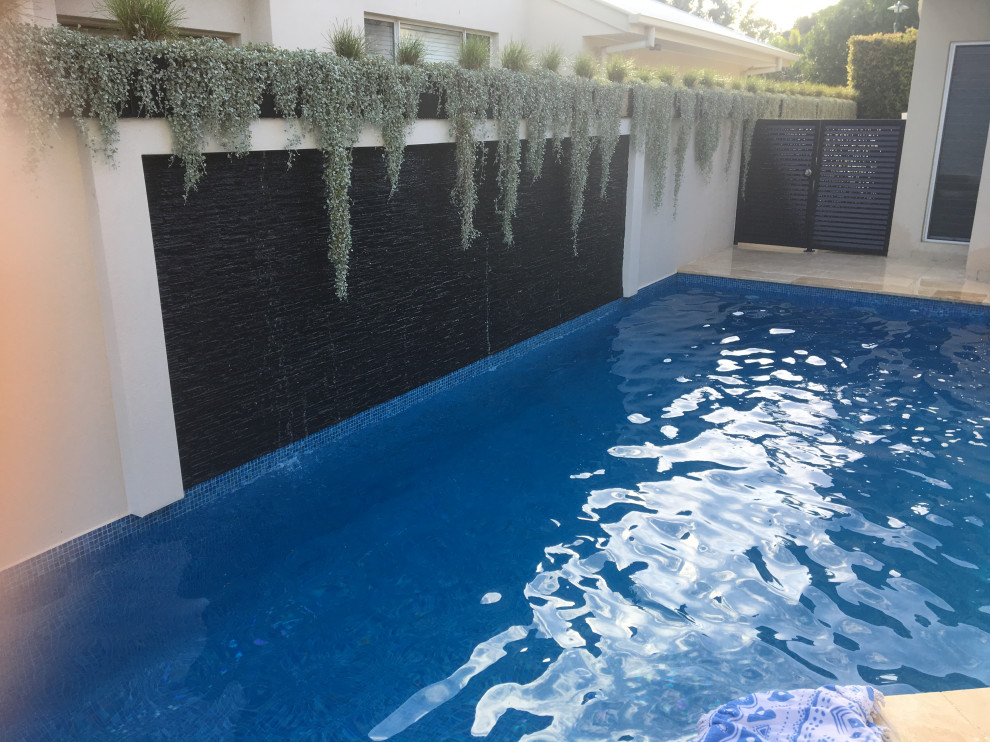 Foto de piscina alargada actual en patio trasero con suelo de baldosas